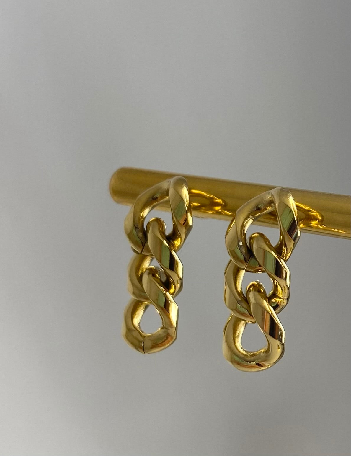 Gold Drop Earring on gold display with white backround