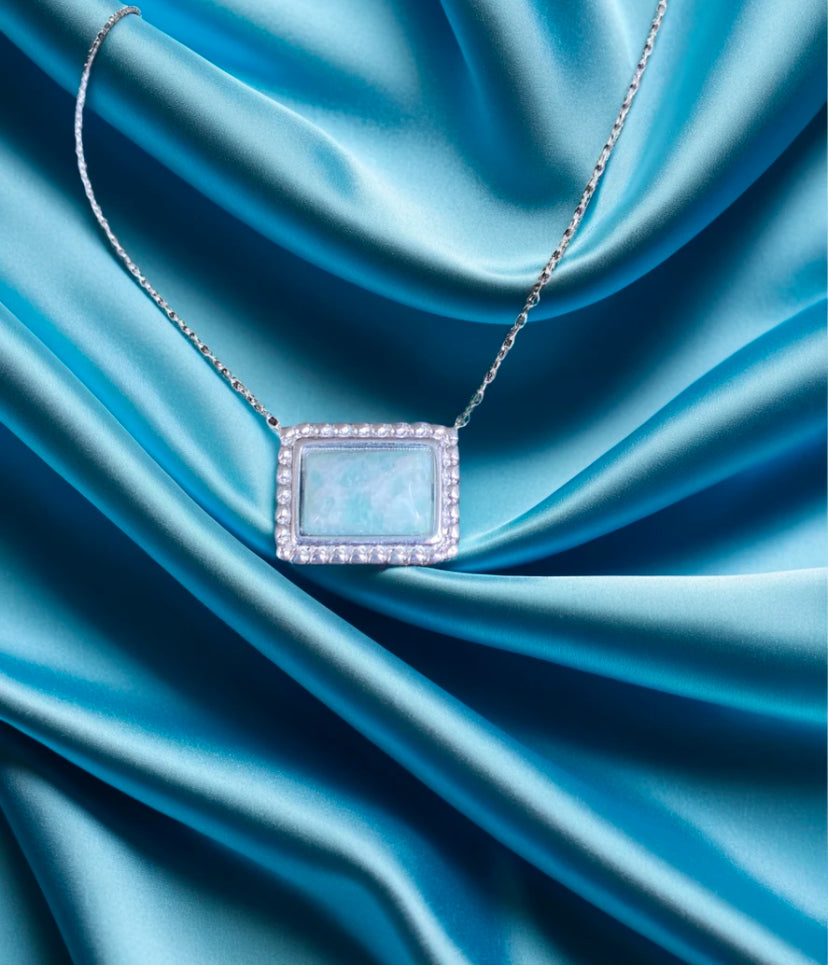 green-blue pendant in silver on blue silk background