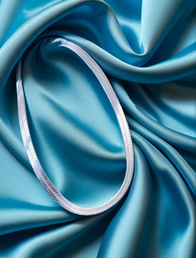 silver snake skin necklace on blue silk background
