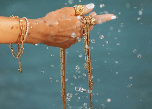 Female hand holding gold jewellery over water