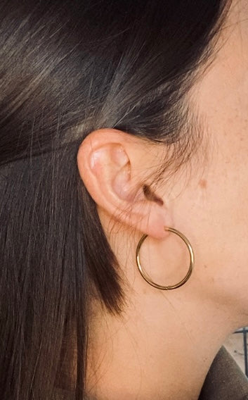 side profile on brunette caucasian woman wearing gold hoop earrings.