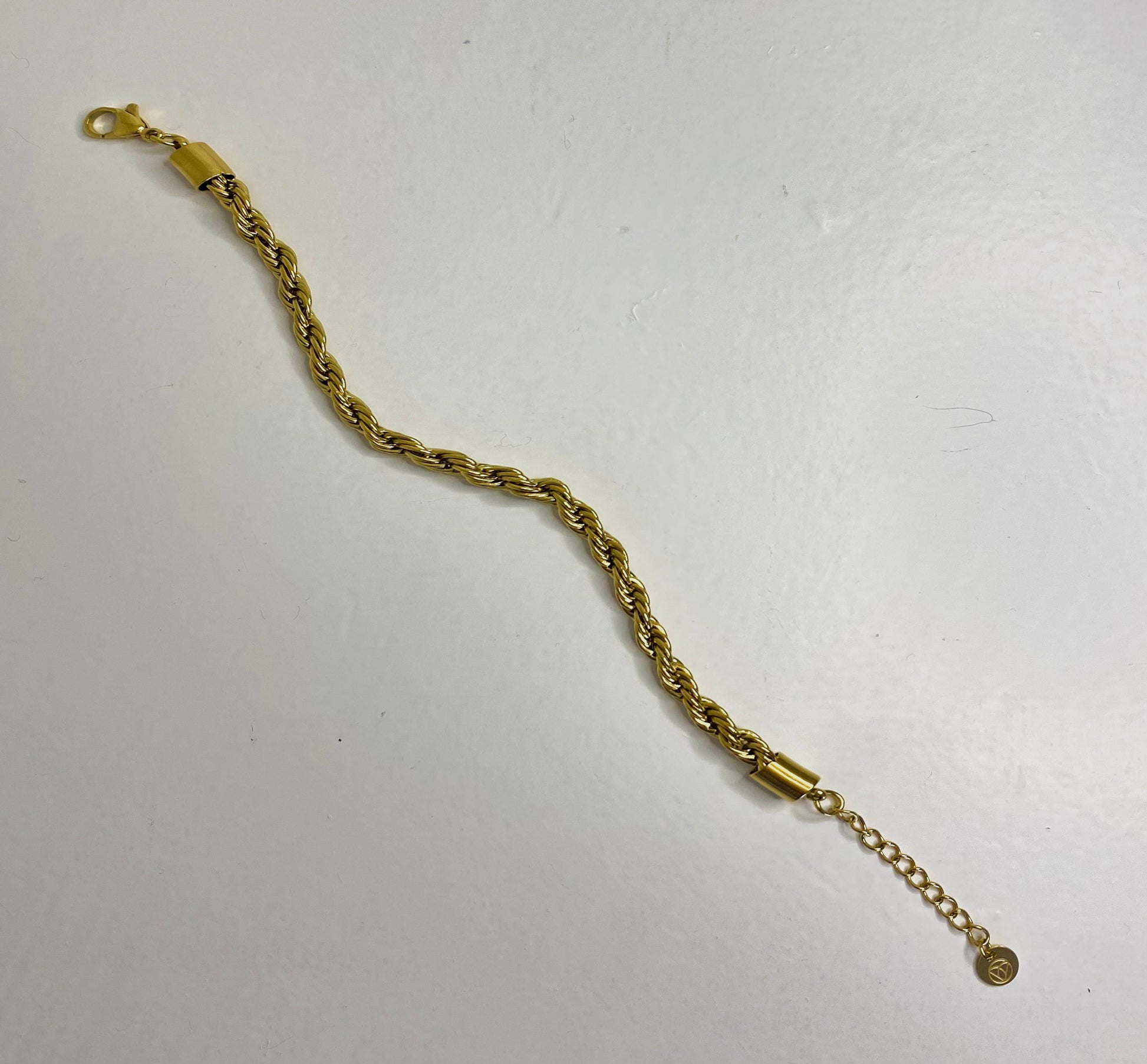 Thick gold twist bracelet on plain white background