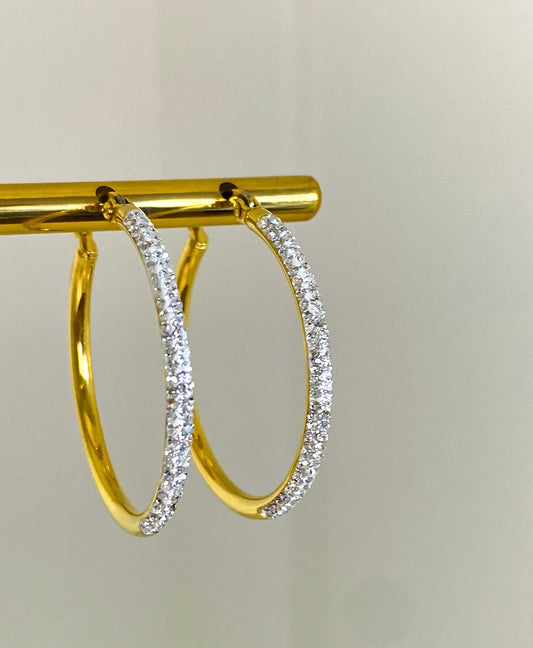 Gold plated Sparkling Hoop Earrings with diamond detail. Gold display and a beige background