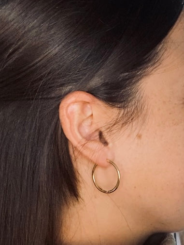 side profile of brunette caucasian woman wearing gold hoop earrings.