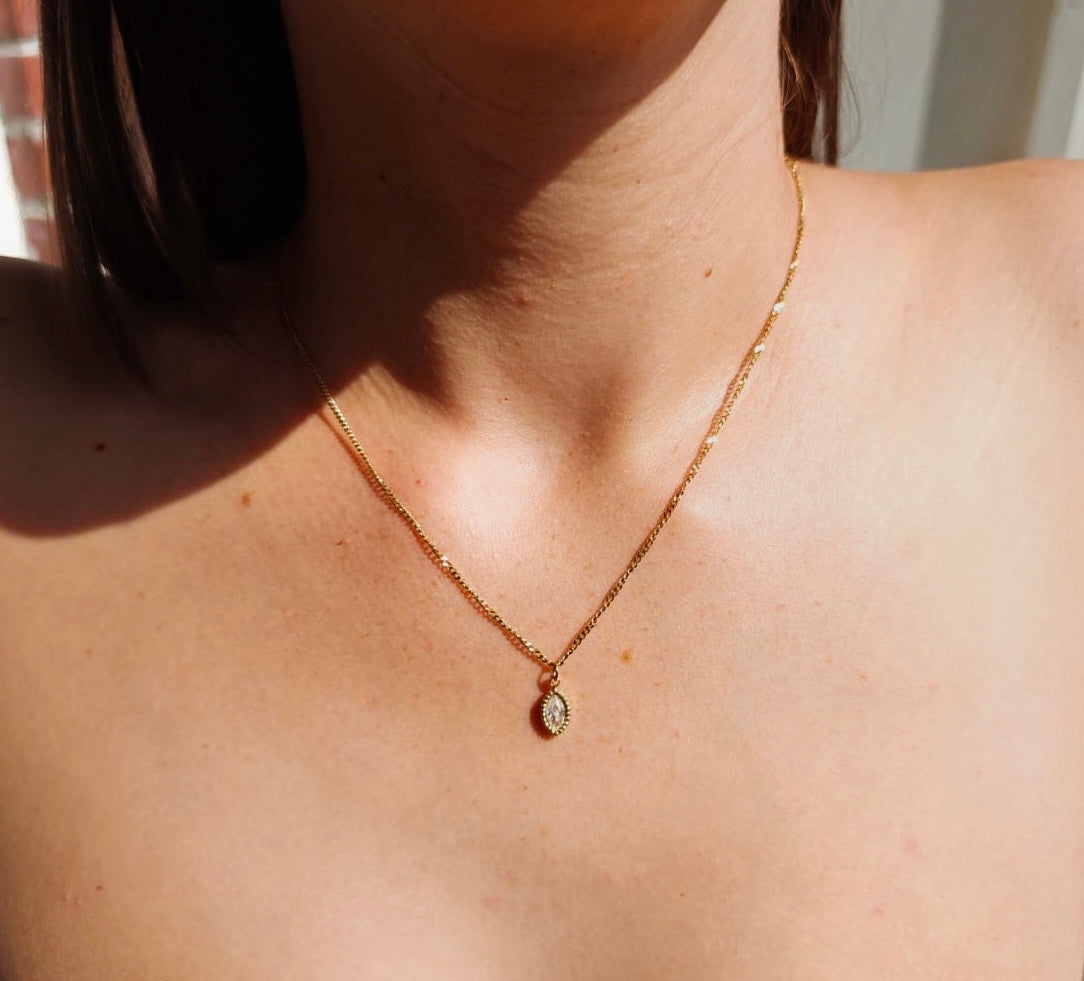 brunette model wearing a gold plated marquise cut diamond necklace in the sunshine