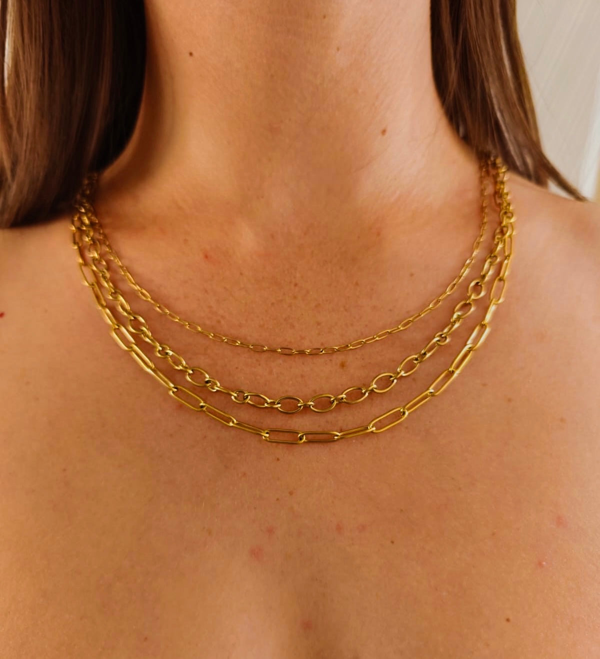 brunette female model wearing layered gold chain