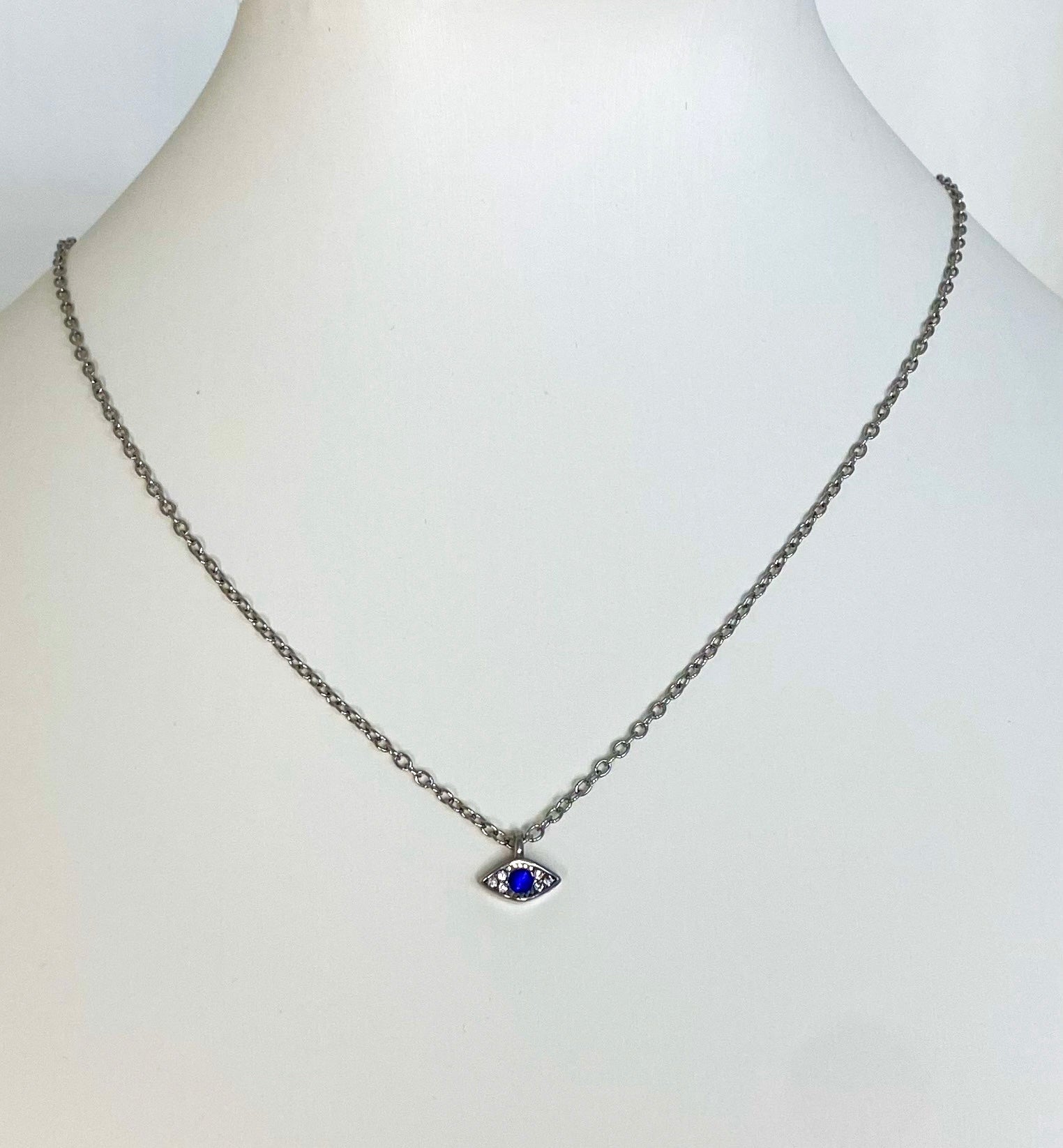 silver chained necklace with evil eye pendant on a white manakin 