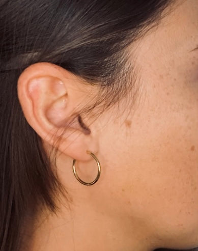 side profile on brunette caucasian woman wearing gold hoop earrings.